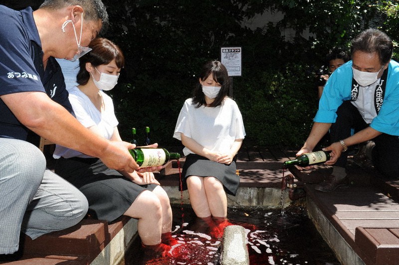 足湯にワインを注ぐ庄内たがわ農協の太田組合長(右端)ら=山形県鶴岡市湯温海のあつみ温泉で