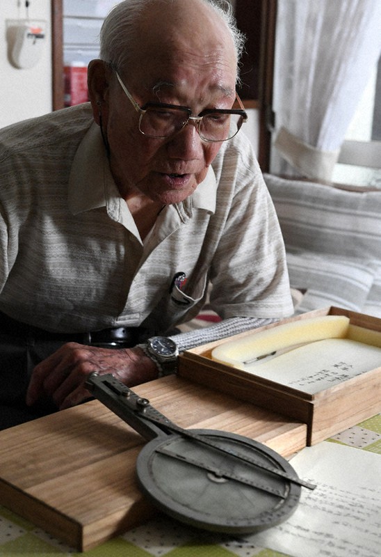 爆撃などの位置を計算する「飛行計算盤」を手に戦時中を振り返る小林近義さん。終戦から75年がたち「戦友はもうほとんどいない」と語った=東京都渋谷区で7日、竹内紀臣撮影