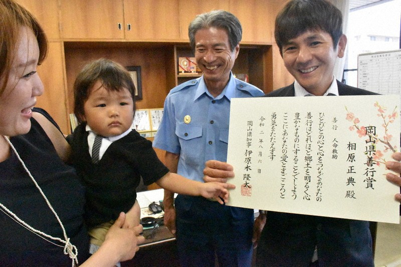 表彰された相原正典さん(右)と妻の麻里さん(左)、息子の颯介ちゃん。中央は西村隆男・岡山中央署長=岡山市中区の同署で