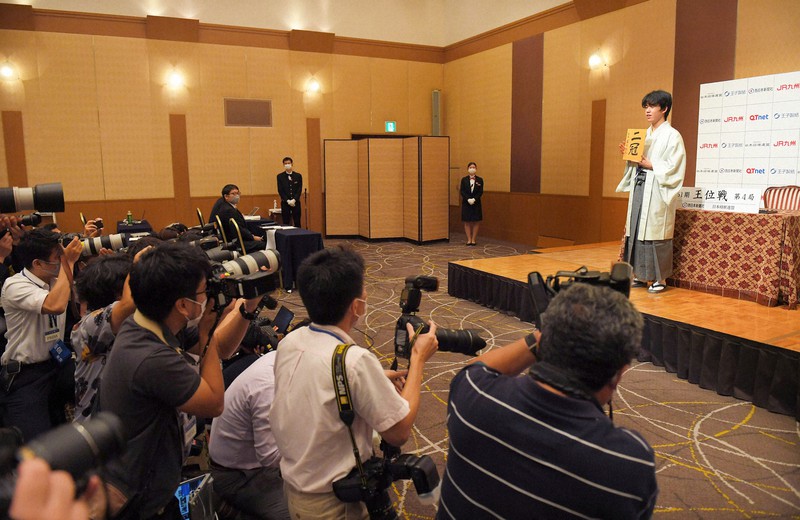 最年少で2冠を達成し、自筆の色紙を掲げて写真撮影に応じる藤井聡太新王位(右)=福岡市中央区で2020年8月20日午後6時33分、津村豊和撮影