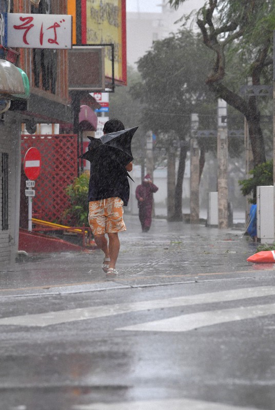 傘も役に立たない暴風雨の中を歩く観光客ら=那覇市で2019年9月、森園道子撮影