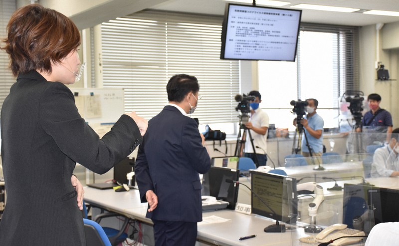 鳥取県の新型コロナウイルス対策本部会議に臨む平井伸治知事の斜め後ろに立つ手話通訳者(左)。テレビカメラは各局1台ずつ=鳥取市の同県庁で2020年8月20日午後3時40分、阿部絢美撮影