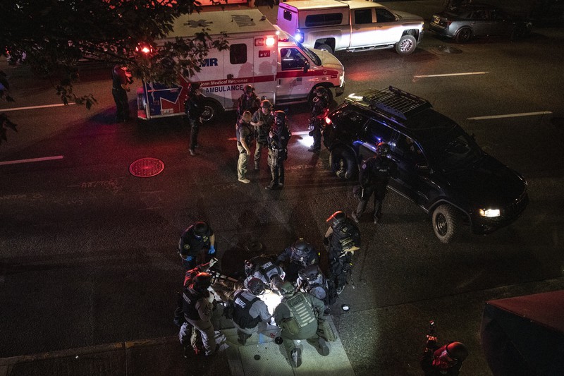 29日、米西部オレゴン州ポートランドで、銃撃された男性を救護する医療関係者=AP
