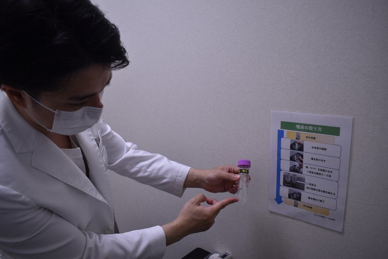 検体となる唾液の採取方法について説明する日本橋れいわ内科クリニックの井内裕之院長=2020年8月14日午後4時5分、島田信幸撮影
