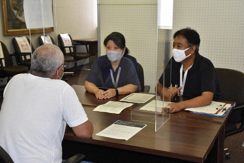 外国人(手前)の生活相談を受け、各種貸付金などについて説明する市職員ら=津市の津リージョンプラザで