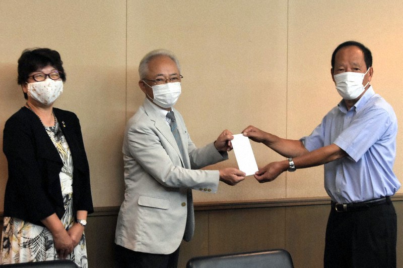 義援金を古谷久人・市共同募金委員会会長(中央)に手渡す山本卓美会長(右)=三重県名張市丸之内の市総合福祉センターふれあいで、衛藤達生撮影