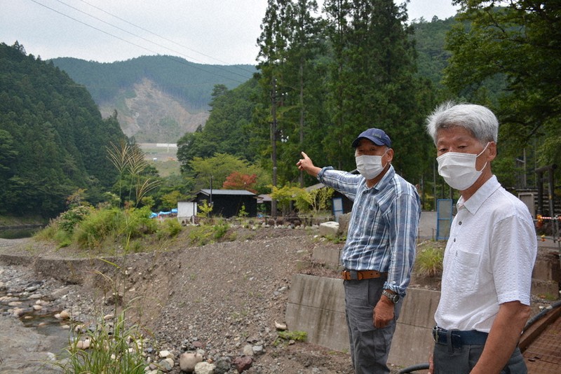 天川村の坪内地区で植樹活動を進めている西岡さん(左)と井頭さん。奥に見える山肌は、2011年9月の紀伊半島豪雨で深層崩壊を起こした箇所=奈良県天川村坪内で、萱原健一撮影