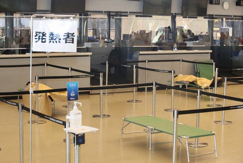 台風での孤立を想定し、関西国際空港で7月に実施された新型コロナウイルス対応訓練。37.5度以上の発熱者を3メートル四方の仕切りで隔離する。発熱者役の2人が簡易ベッドに横たわっている=関西国際空港で2020年7月9日、菱田諭士撮影