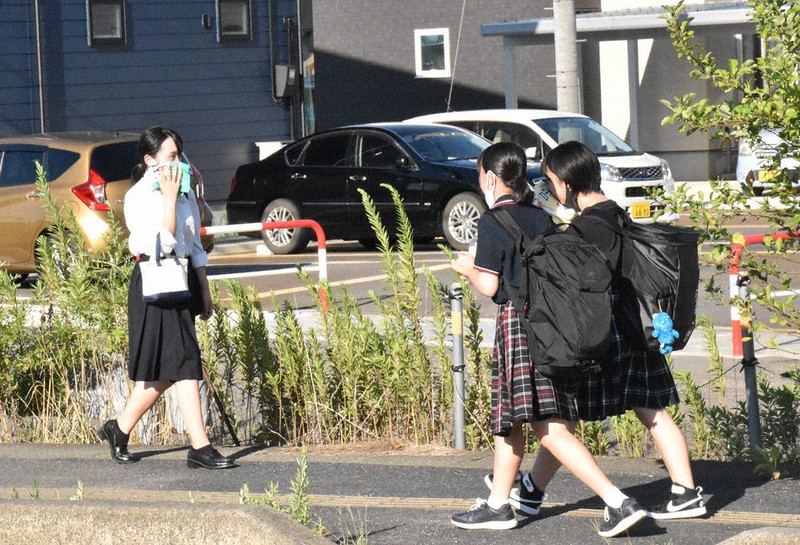 夕方になっても暑さはおさまらず、タオルで汗を拭いながら下校する学生たち=新潟県三条市で、北村秀徳撮影