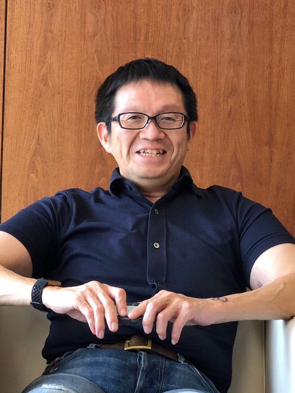 大石剛。執務の服装もシリコンバレー風。スーツではない。イノベーションレポートには大石の一文が巻末に寄せられ、そこでは、「役職定年とそれに伴う給与の引き下げ」も改革の一環として実行すると書かれている。