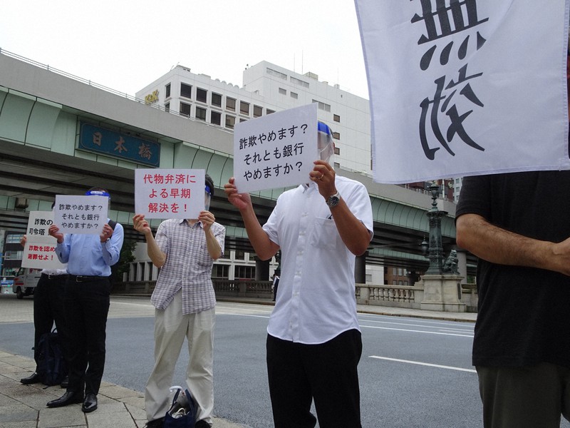 「日本橋」の看板を背に、スルガ銀行に抗議する購入者=東京都中央区で9月2日午前8時、今沢真撮影