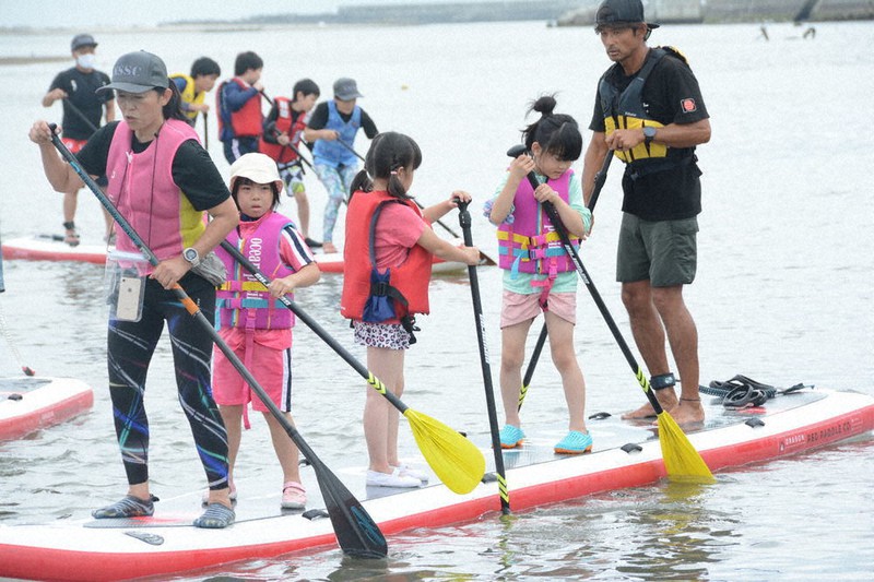 名取川でSUPをこいで楽しむ閖上小中学校の児童・生徒ら=宮城県名取市閖上で