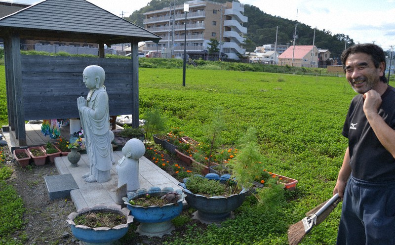旧役場庁舎跡地に設置された地蔵の周りの花壇を整備する岩間英二さん。職員だった同級生を亡くした=岩手県大槌町で