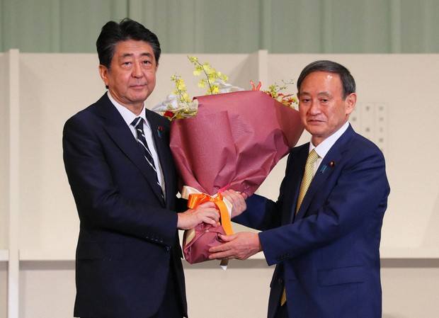 自民党総裁選終了後、安倍晋三首相(左)に花束を渡す次期首相の菅義偉氏=東京都内のホテルで2020年9月14日、長谷川直亮撮影