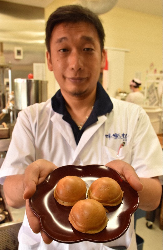 「蜂蜜まん」を手にする水谷栄希社長=津市大門の蜂蜜まん本舗で2020年9月4日、朝比奈由佳撮影