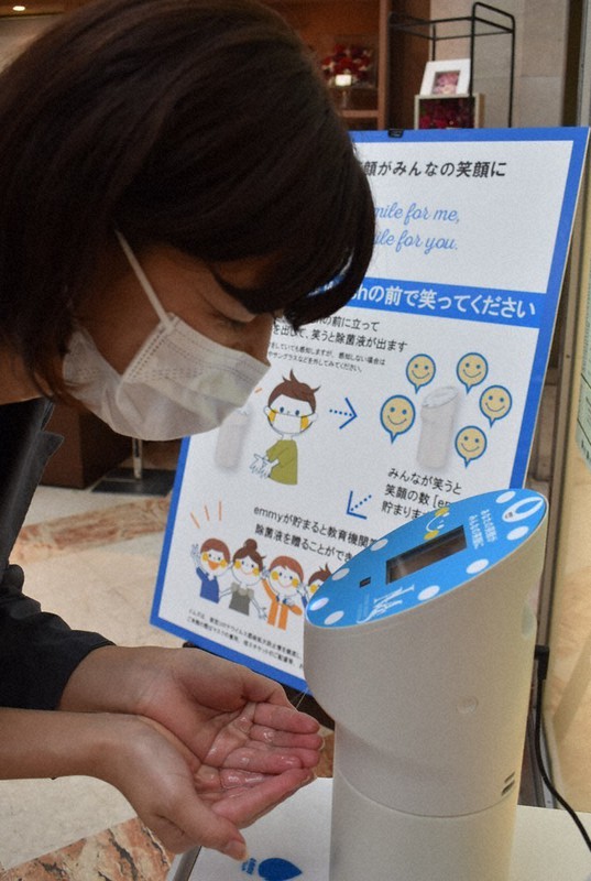 マスク越しの笑顔を感知し消毒液を噴霧するエミーウォッシュ=福岡市中央区で、末永麻裕撮影