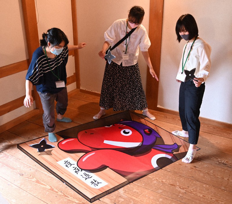 鶴ケ城の南走り長屋に設置された赤べこのトリックアート。制作した会津大短期大学部の(左から)遠藤すずみさん、丹治帆乃香さん、天童萌々美さん=福島県会津若松市追手町で2020年9月13日、三浦研吾撮影
