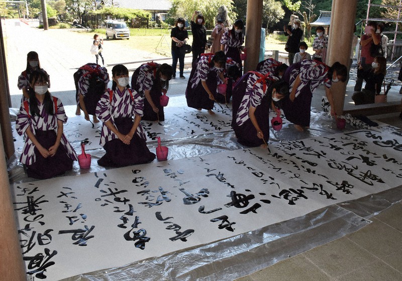 世界の平和と新型コロナウイルスの感染終息を願って、書の作品を仕上げた県立岐阜総合学園高書道部の生徒=岐阜市御手洗の岐阜護国神社で
