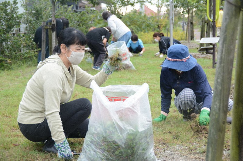 マスクを着用し、談笑しながら草刈りをする参加した住民ら=宮城県岩沼市で2020年9月13日午前6時35分、深津誠撮影
