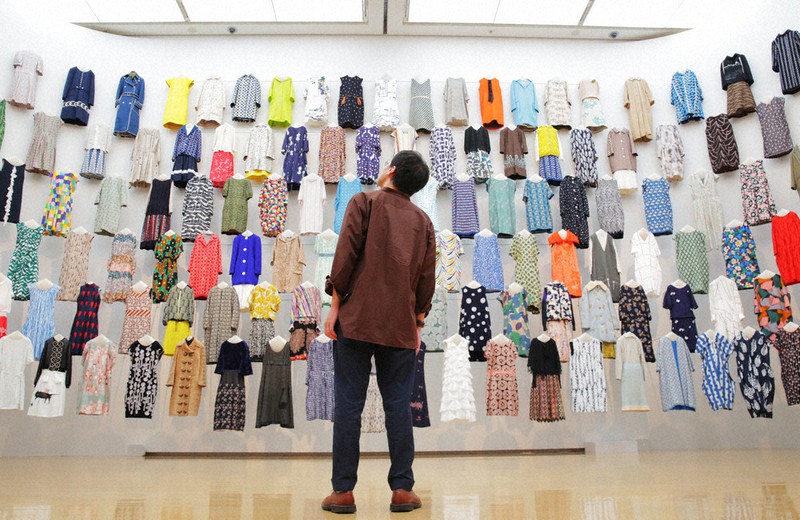 「つづく」展(11月8日まで)でミナペルホネンの服を鑑賞する斎藤幸平さん。無地の布をカットすると中からチョウが現れるなど、飽きないデザインの工夫がなされている=神戸市中央区で2020年9月9日、菱田諭士撮影