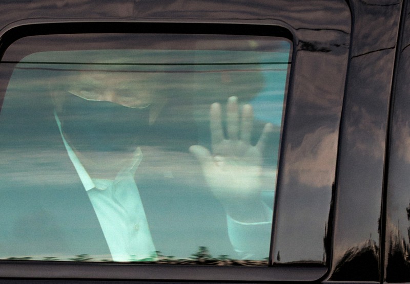車で病院周辺を回り、集まった支持者らに車内から手を振るトランプ米大統領=米首都ワシントン近郊のウォルター・リード陸軍病院近くで2020年10月4日、ロイター