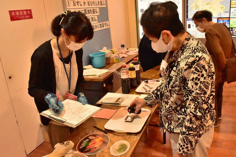 普段使うしょうゆの量を量る参加者(右)=青森市新町の市役所駅前庁舎1階で2020年10月5日、平家勇大撮影