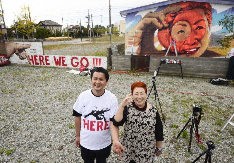 JR双葉駅前に描かれた壁画の前で記念撮影に応じる高崎丈さん(左)と吉田岑子さん=福島県双葉町長塚で2020年10月7日午後4時26分、渡部直樹撮影