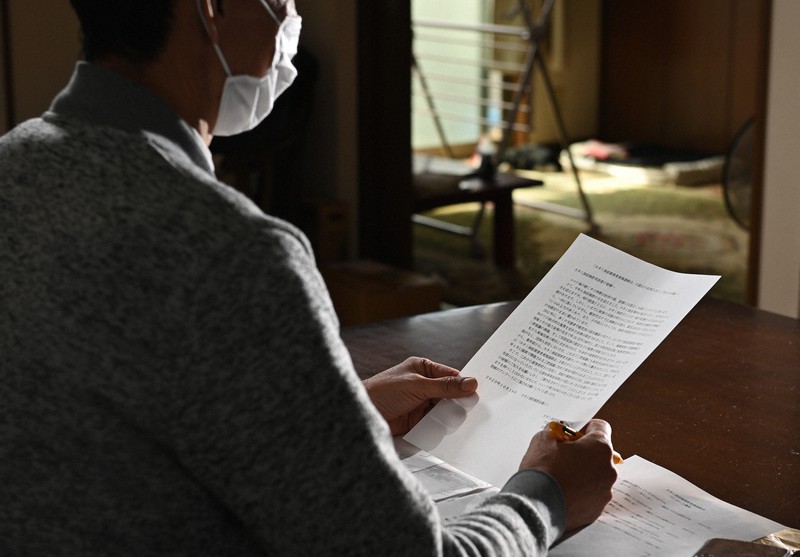 カネミ油症被害者東海連絡会の設立を知らせるチラシを読み返す共同代表の男性=名古屋市内で2020年10月6日、兵藤公治撮影