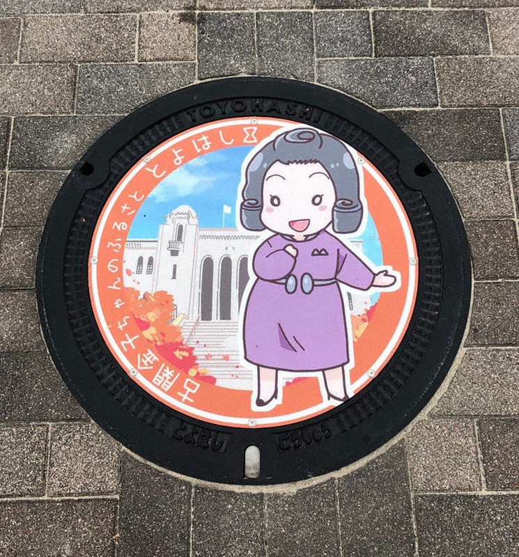 古関金子さんをモチーフにしたマンホール「豊橋市公会堂と洋服姿の古関金子さん」=愛知県豊橋市提供