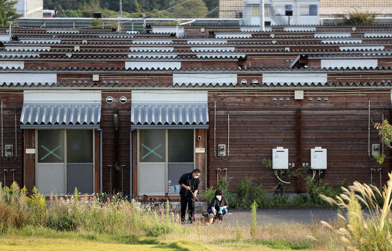 東日本大震災の際に建設された仮設住宅で、愛犬を散歩させる大沼五木さん(左)と妻大沼祐子さん。入居者は少なく、雑草も背を伸ばしていた=福島県本宮市で2020年10月4日、小川昌宏撮影