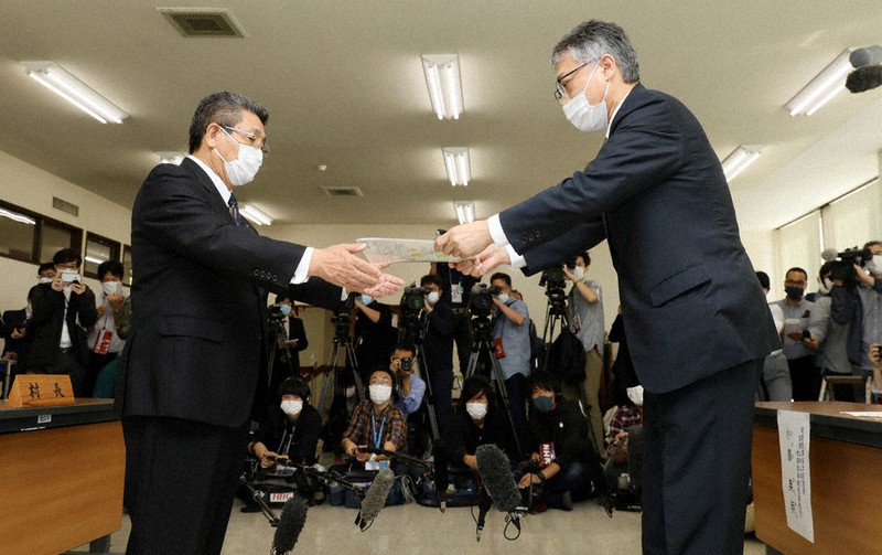 経産省の担当者(手前右)から核のごみ最終処分場選定の文献調査申し入れ書を受け取る高橋昌幸村長(同左)=北海道神恵内村で2020年10月9日午後1時31分、貝塚太一撮影