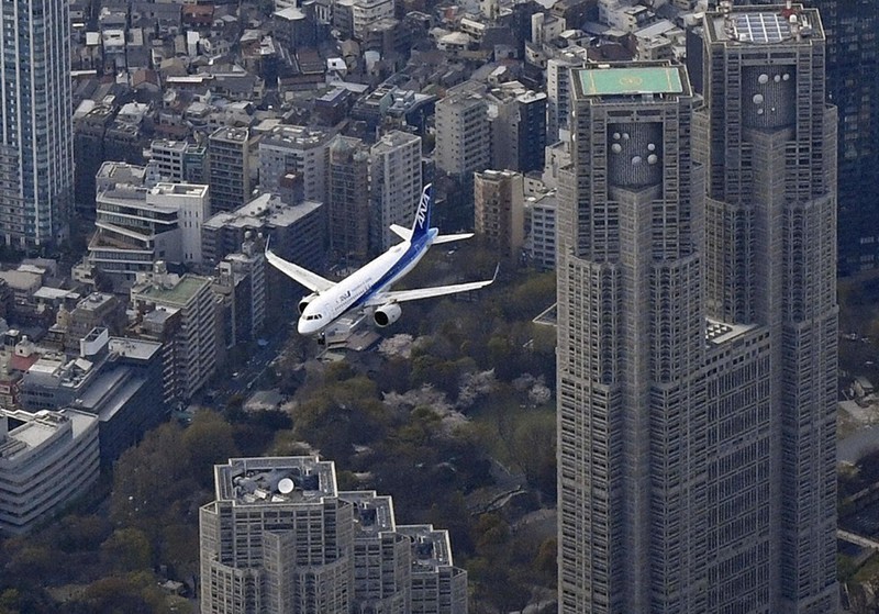 羽田新ルートを使い、都心上空を飛行する航空機。右は東京都庁=2020年4月3日午後3時21分、本社ヘリから