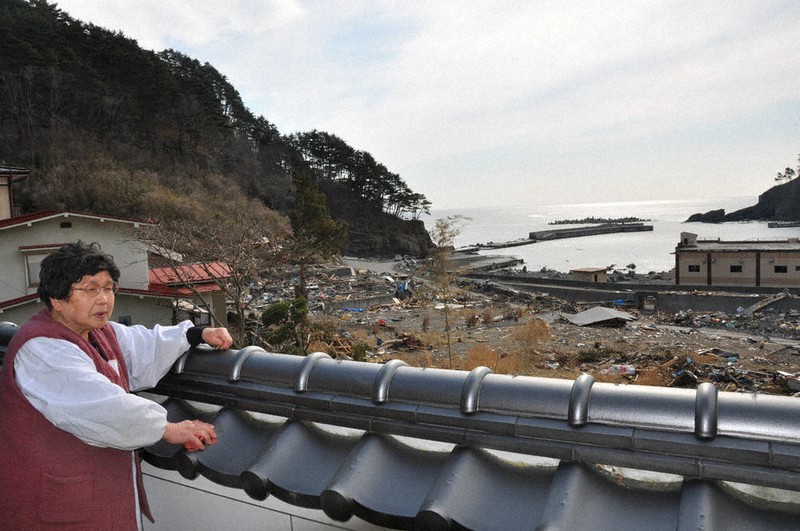 1人暮らしの自宅兼旅館から、がれきが続く沿岸を見つめる畠山照子さん=岩手県田野畑村で2011年3月29日、工藤哲撮影