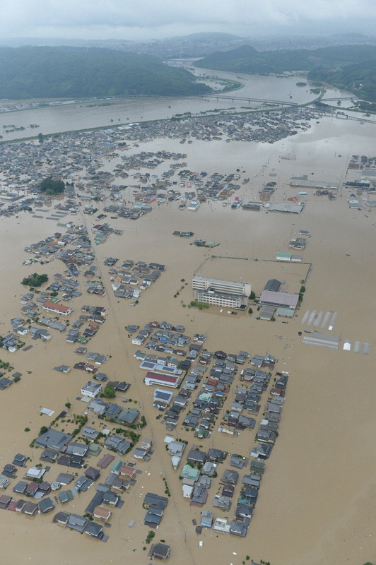西日本豪雨によって堤防が決壊し、濁流に覆われた市街地。奥は高梁川=岡山県倉敷市真備町地区で2018年7月7日午後0時41分、本社ヘリから加古信志撮影