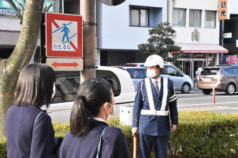 歩行者の横断が禁止されている香川県道で通学者らを見守る警察官=高松市天神前で、川原聖史撮影