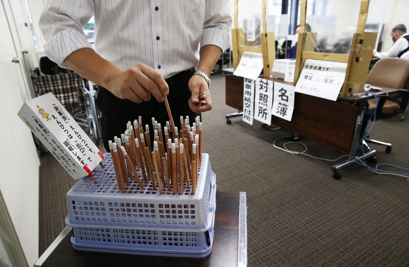 期日前投票所で、投票用の鉛筆を消毒する選管職員=大阪市中央区で2020年10月16日午後4時4分、小出洋平撮影