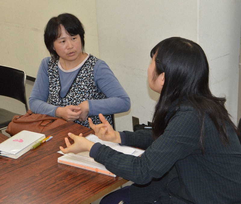 避難者の調査をしている大学生のインタビューに答える森松明希子さん(左)=大阪市内で2015年10月27日