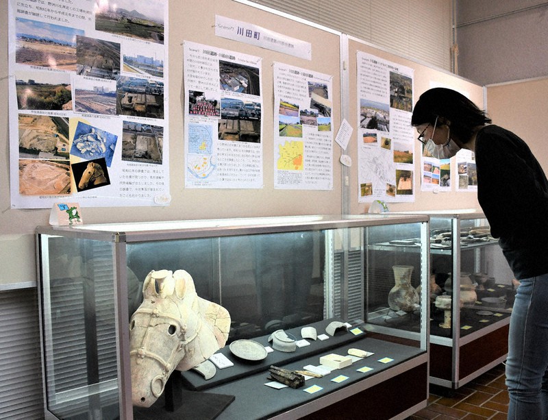 発掘調査の資料写真で守山の変遷をたどる会場。遺跡からの出土品も多数並ぶ=滋賀県守山市服部町の守山市立埋蔵文化財センターで、礒野健一撮影