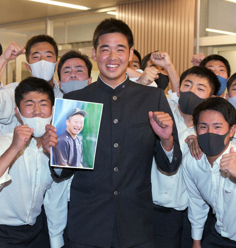 オリックスの1位指名が確定し、オリックスの中嶋監督代行の写真を手にチームメートと記念撮影に応じる山下選手(中央)=福岡市中央区で2020年10月26日午後5時57分、須賀川理撮影