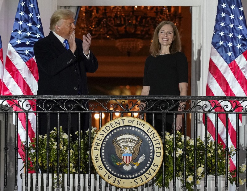 米最高裁判事への就任宣誓後、ホワイトハウスのバルコニーでトランプ大統領(左)から拍手を受けるバレット氏=2020年10月26日、AP