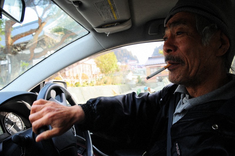 親類に借りた車で街を巡り、慈恩寺(左奥)に戻った菅野徳一さん。「ここらは代わり映えしねえなあ」=岩手県陸前高田市広田町で2011年4月7日午前6時52分撮影
