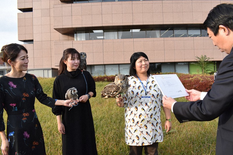 いけふくろうカフェの元オーナー、松岡真理さん(左端)らの手や肩に止まり、前橋市の山本龍市長(右端)から「前橋市赤城山特別住民票」を交付されたフクロウ=前橋市大手町で2020年10月28日、鈴木敦子撮影