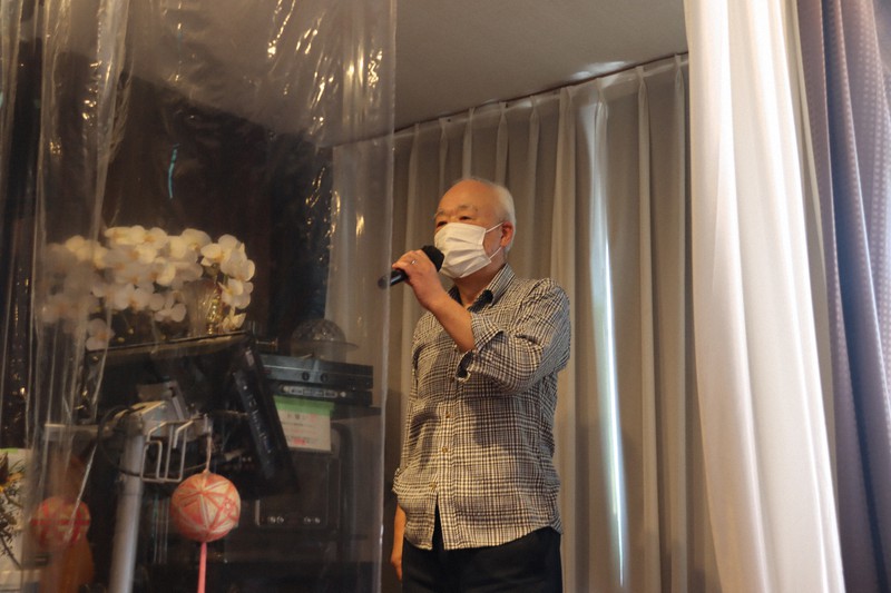 感染防止用のビニールの幕で仕切ったステージでマイクを握る萩谷繁夫さん=千葉県佐倉市のトトロパートⅡで2020年10月26日午前11時32分、金子淳撮影