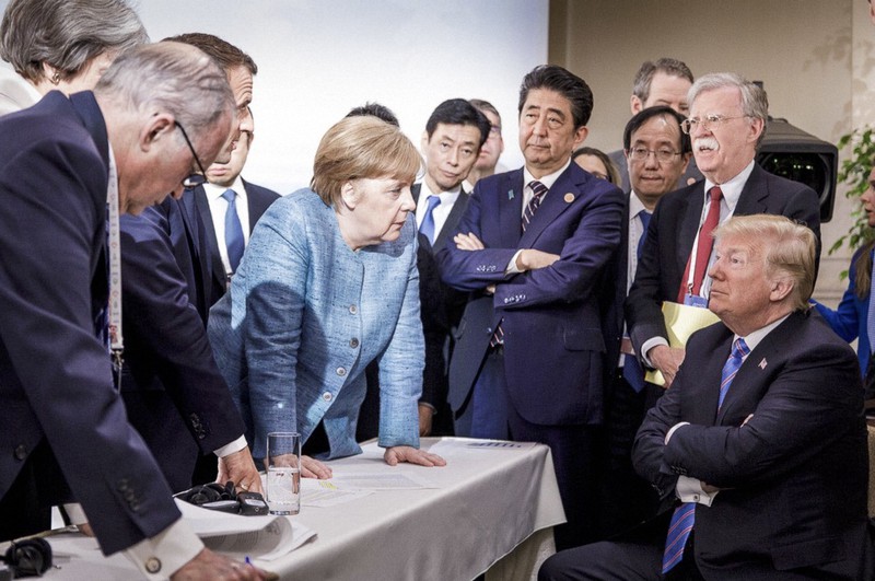 主要7カ国首脳会議でドナルド・トランプ米大統領(右)の前のテーブルに手をついて詰め寄るアンゲラ・メルケル独首相。様子を見守る安倍晋三前首相の姿も=カナダ・シャルルボワで2018年6月9日、独政府提供・AP