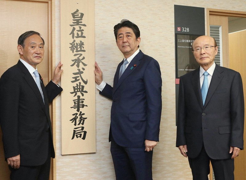 杉田和博官房副長官(右)は政府の主な政策決定に関わってきた。皇位継承式典事務局の「看板掛け」で、当時の安倍晋三首相(中央)、菅義偉官房長官(左)と並ぶ杉田氏=内閣府で2018年8月1日(代表撮影)