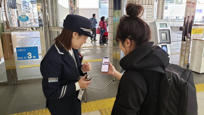 スマートフォンに入ったデジタルチケットを確認する駅係員