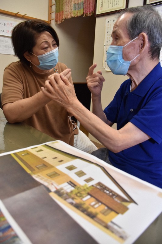 完成イメージ図を前に、触手話で盲ろう者と住宅型有料老人ホームの計画について話す瀬戸節子事務局長(左)=和歌山市美園町5のNPO法人和歌山盲ろう者友の会で2020年9月23日午前11時56分、木原真希撮影