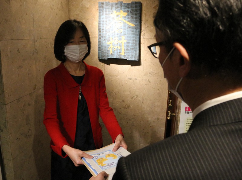 名古屋市の感染防止対策協力店の1号店に認定され、市職員からステッカーを受け取る、会員制クラブ「蒼樹」の牛田順子さん=名古屋市中区錦3の同店で2020年11月11日午後2時42分、野村阿悠子撮影