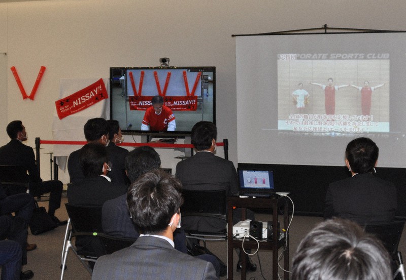 スクリーンに上映された応援団のエール動画に見入る野球部員らと、東京本部から壮行会にリモート参加した藤本常務(左の画面)=大阪市中央区の日本生命本店で2020年11月16日午後0時43分、荻野公一撮影
