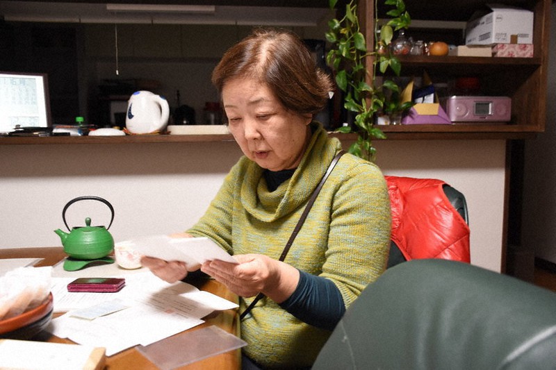 複数の病院の診察券を見つめる金野ミエ子さん=岩手県陸前高田市米崎町で